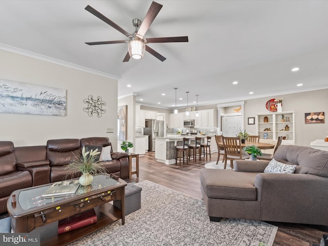 living room with light wood-type flooring, ceiling fan, and ornamental molding