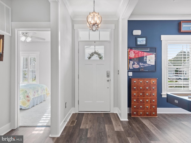 foyer entrance with crown molding, dark wood-type flooring, and ceiling fan with notable chandelier