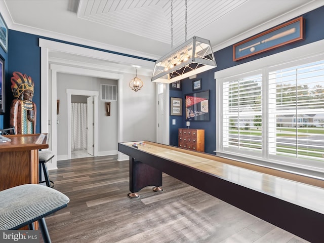 recreation room with wood-type flooring, an inviting chandelier, a wealth of natural light, and ornamental molding