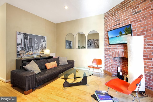 living room with wood-type flooring and a brick fireplace