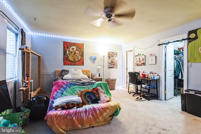 carpeted bedroom with ceiling fan and a spacious closet