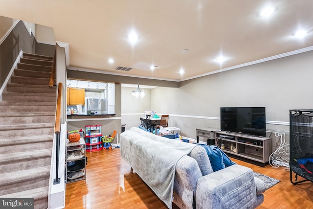 living room with visible vents, crown molding, stairway, and wood finished floors