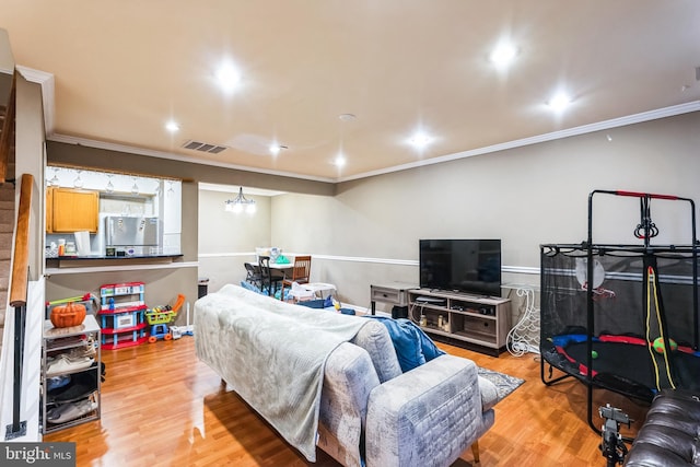 living room featuring light wood-style floors, visible vents, crown molding, and recessed lighting