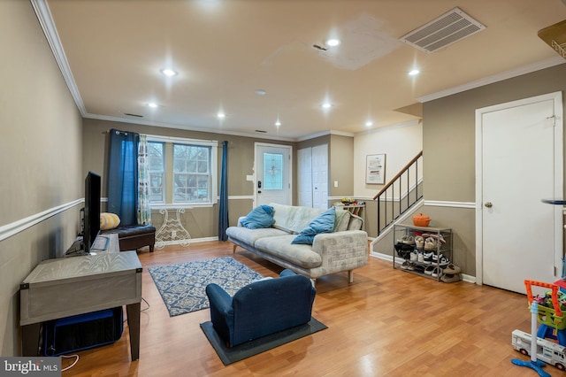 living area featuring visible vents, crown molding, stairway, and wood finished floors