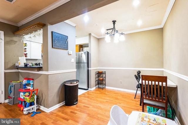 interior space with light wood-type flooring, baseboards, ornamental molding, and freestanding refrigerator