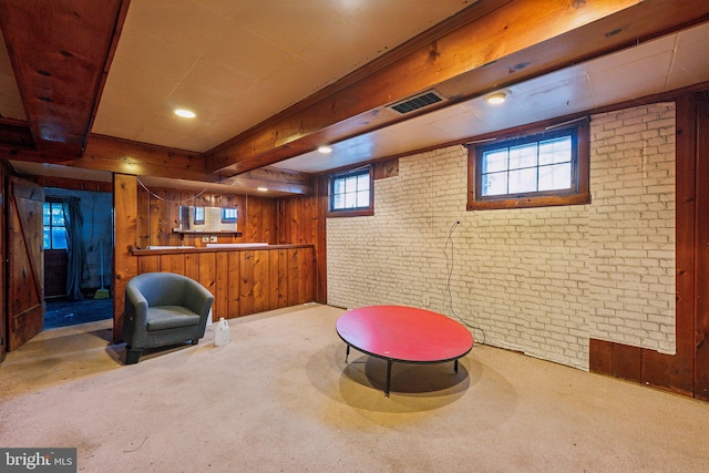 sitting room featuring light carpet, wood walls, a healthy amount of sunlight, and brick wall