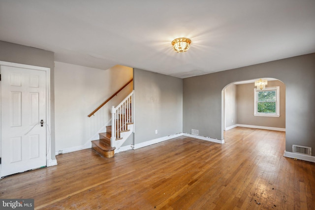 empty room featuring wood-type flooring and a chandelier