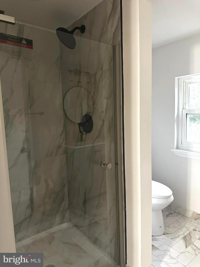 bathroom featuring toilet and a shower with shower door