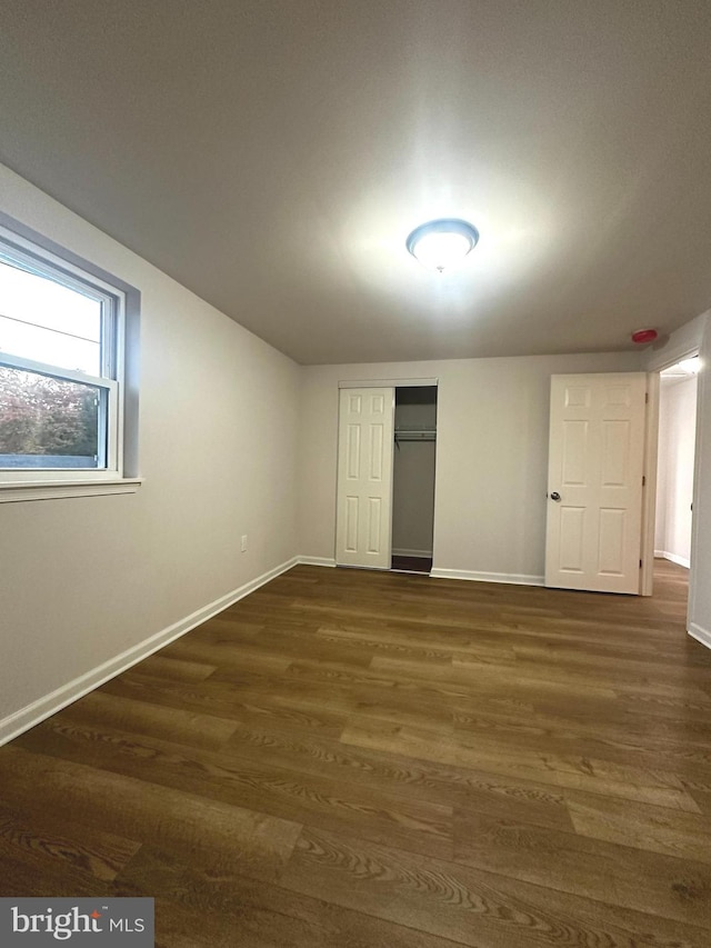 unfurnished bedroom with a closet and dark wood-type flooring