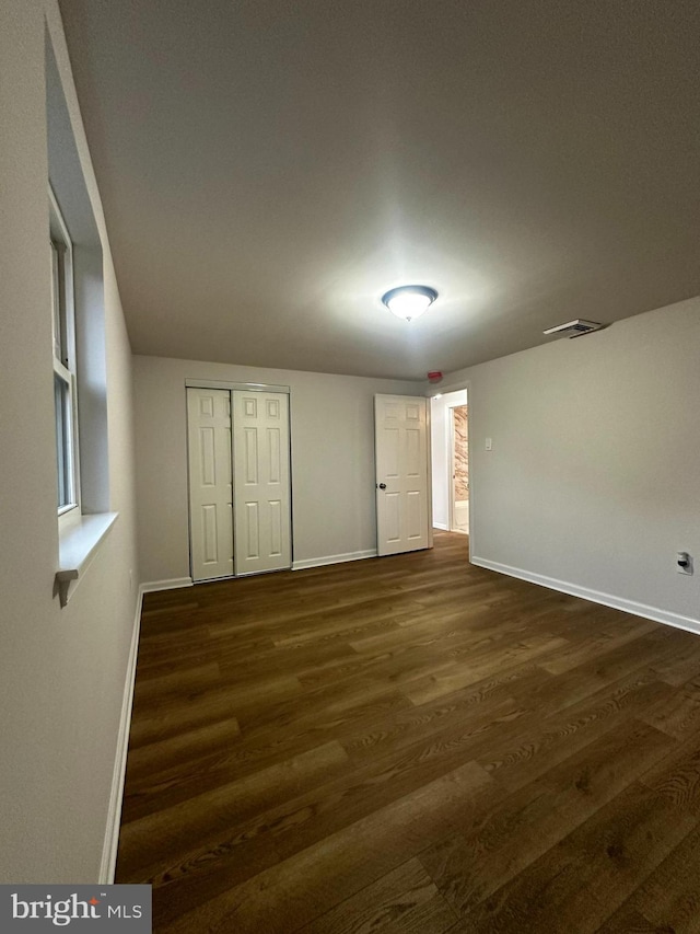 unfurnished bedroom featuring dark wood-type flooring and a closet