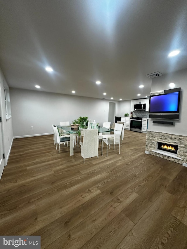 unfurnished dining area with a stone fireplace and dark hardwood / wood-style floors