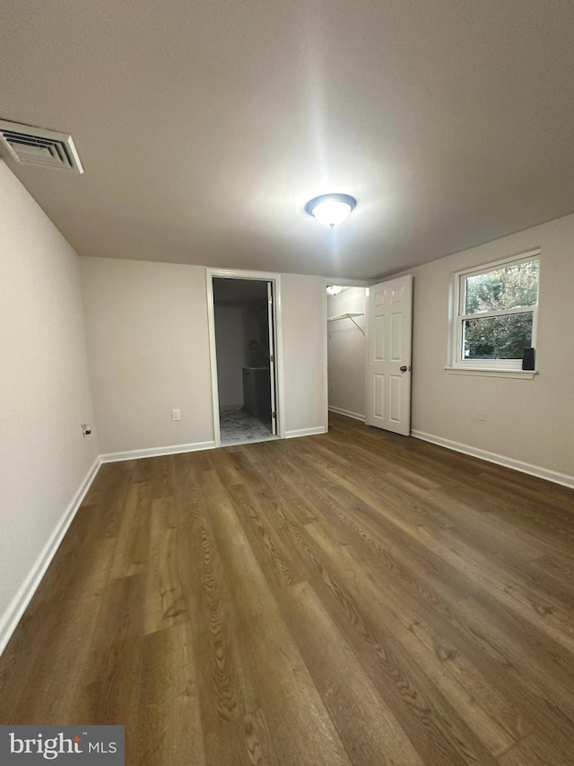 unfurnished bedroom with connected bathroom, hardwood / wood-style floors, a walk in closet, and a closet