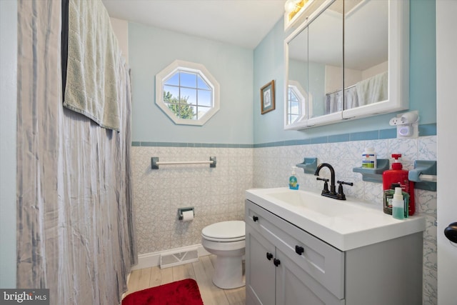 bathroom featuring wood-type flooring, vanity, toilet, and tile walls