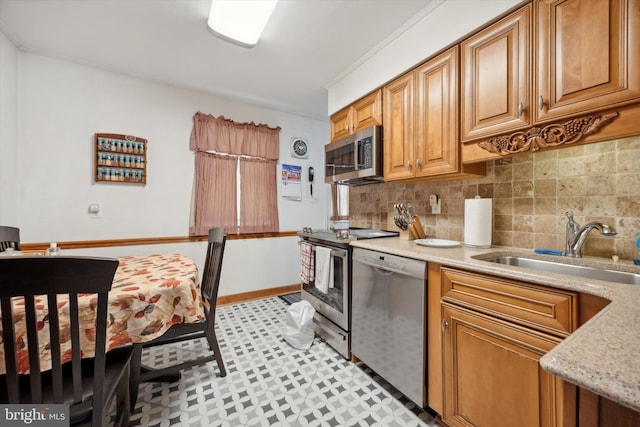 kitchen with sink, crown molding, tasteful backsplash, light stone counters, and stainless steel appliances