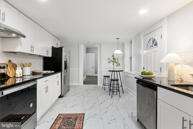 kitchen featuring decorative backsplash, appliances with stainless steel finishes, white cabinetry, decorative light fixtures, and ventilation hood