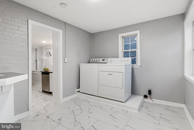 washroom featuring brick wall and washing machine and clothes dryer