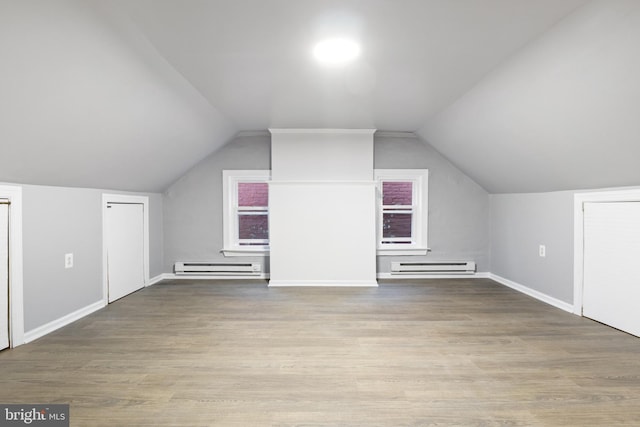 additional living space featuring light hardwood / wood-style flooring, vaulted ceiling, and baseboard heating