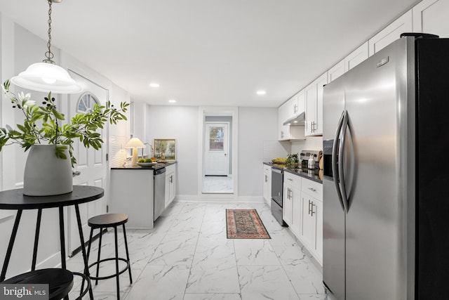 kitchen with hanging light fixtures, backsplash, a breakfast bar, white cabinetry, and stainless steel appliances