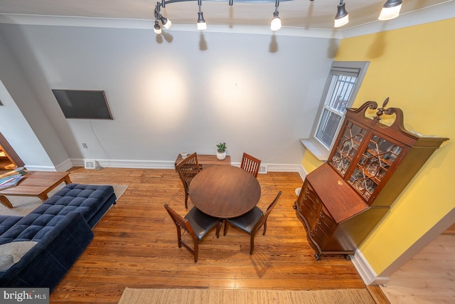 dining space featuring hardwood / wood-style floors, track lighting, and crown molding