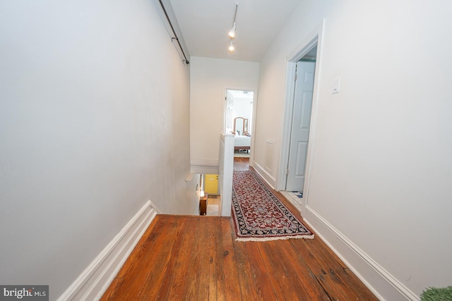 hall with wood-type flooring and track lighting