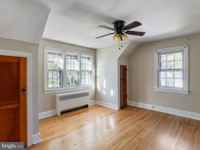 bonus room with light hardwood / wood-style floors, radiator, and ceiling fan