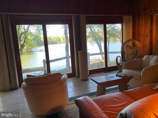 tiled living room featuring plenty of natural light, wood walls, and a water view