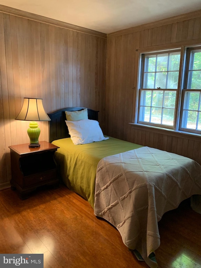 bedroom with wood-type flooring, crown molding, and wooden walls