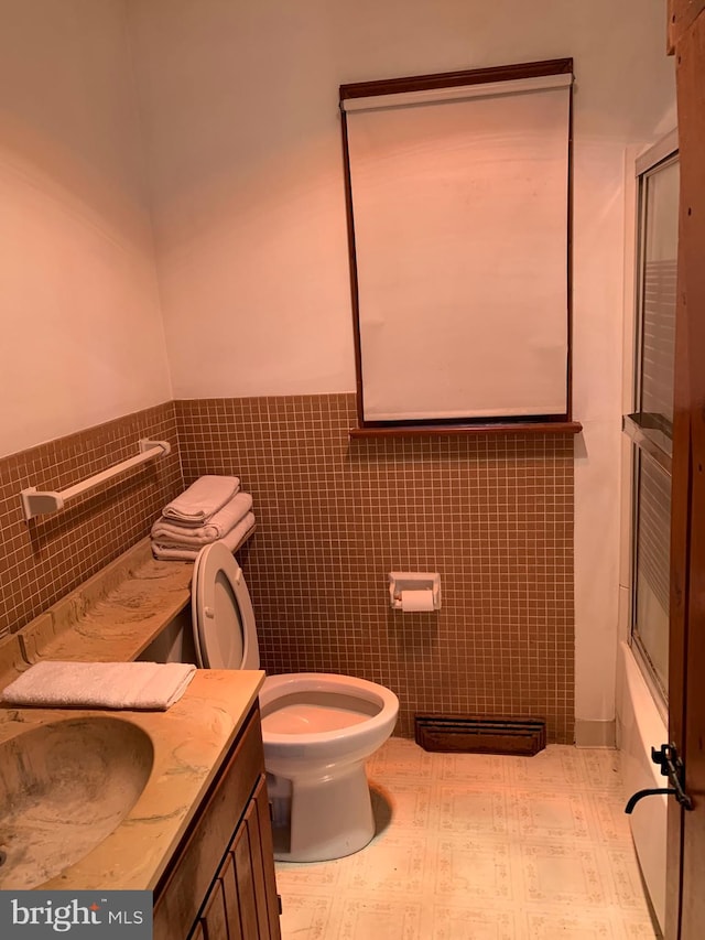 full bathroom with combined bath / shower with glass door, vanity, toilet, and tile walls