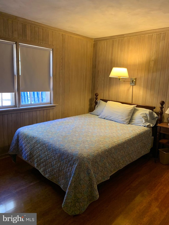 bedroom with wooden walls and dark wood-type flooring