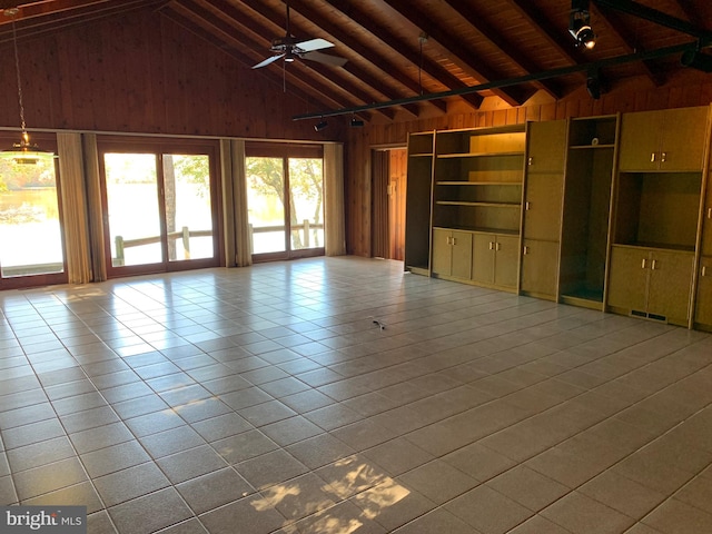 unfurnished living room with high vaulted ceiling, wooden walls, ceiling fan, light tile patterned floors, and wood ceiling