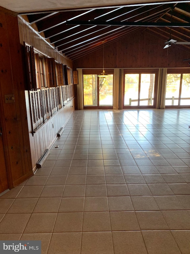 interior space featuring tile patterned flooring, high vaulted ceiling, a wealth of natural light, and wood walls