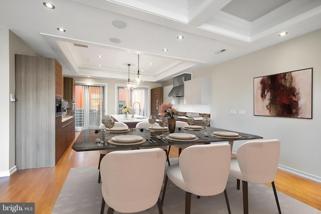 dining room with a raised ceiling, crown molding, sink, and light wood-type flooring