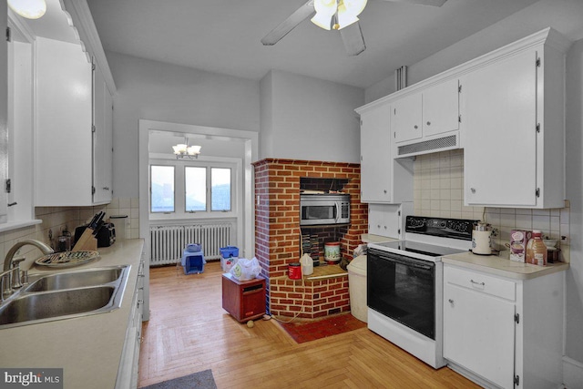 kitchen with decorative backsplash, electric range, sink, and radiator heating unit