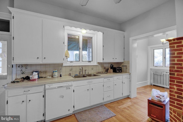 kitchen with white cabinets, radiator heating unit, white dishwasher, and sink