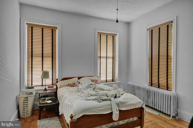 bedroom featuring radiator, light hardwood / wood-style floors, and a textured ceiling