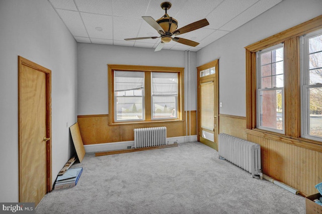 empty room featuring radiator, a paneled ceiling, ceiling fan, and light carpet