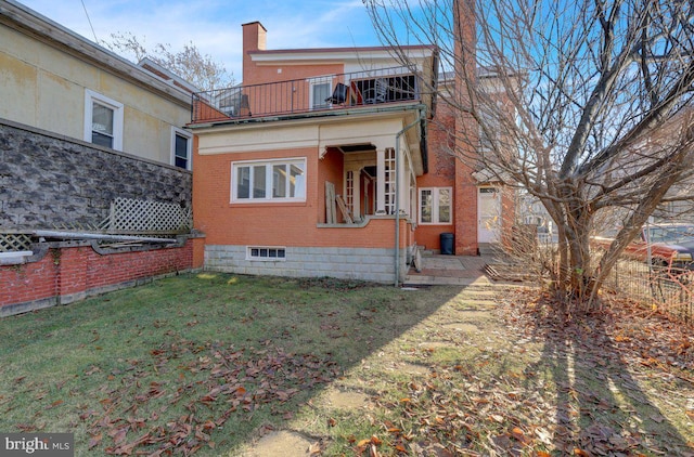 rear view of house featuring a balcony and a lawn