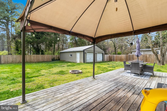 wooden deck with a lawn, a gazebo, an outbuilding, a garage, and an outdoor fire pit