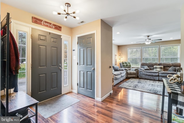 entrance foyer with dark hardwood / wood-style floors and ceiling fan with notable chandelier