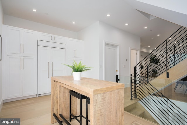 kitchen featuring white cabinetry, a kitchen breakfast bar, a kitchen island, paneled built in fridge, and light wood-type flooring