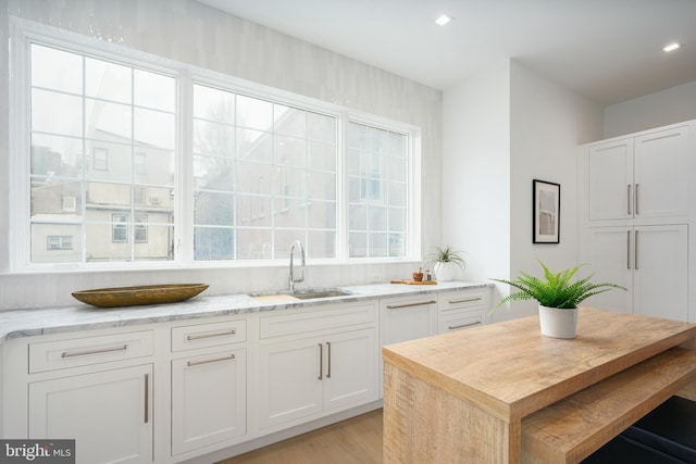 kitchen featuring white cabinets, light hardwood / wood-style floors, plenty of natural light, and sink