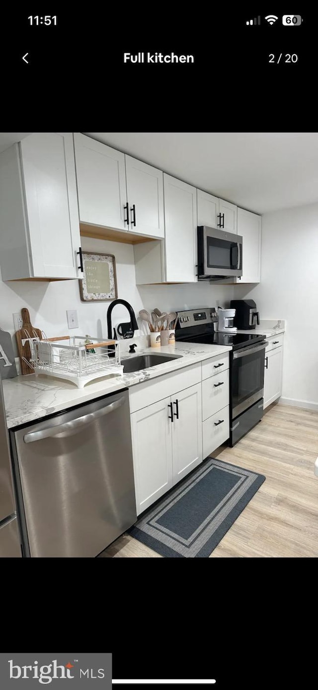 kitchen with light hardwood / wood-style floors, white cabinetry, sink, and stainless steel appliances