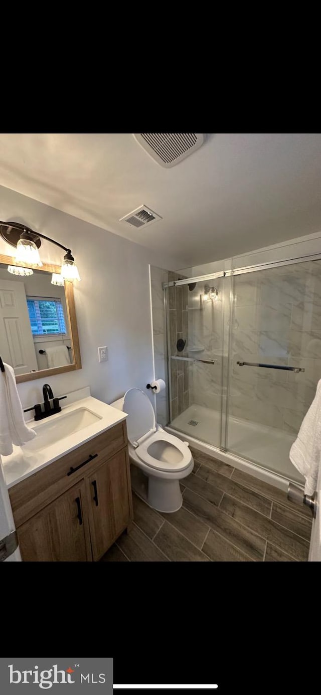 bathroom featuring walk in shower, vanity, and toilet