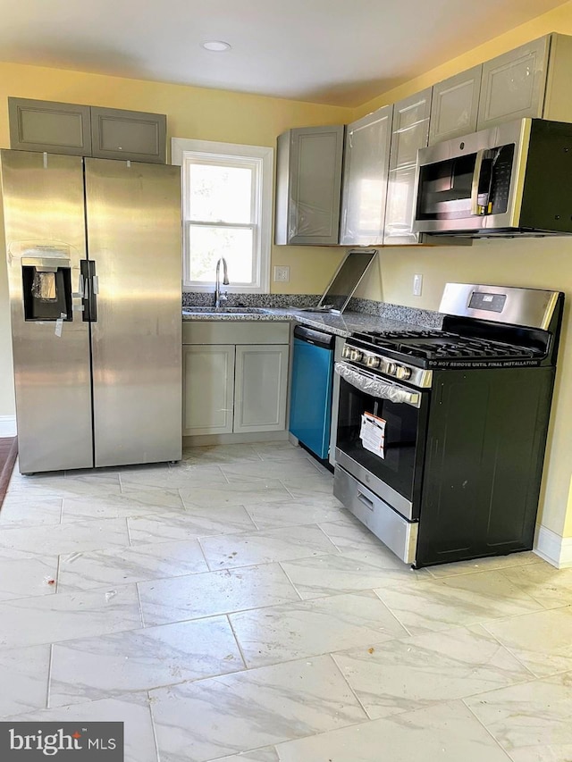 kitchen featuring stainless steel appliances, sink, and gray cabinetry