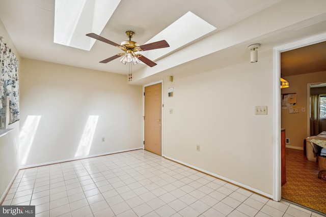 spare room featuring a skylight, ceiling fan, and light tile patterned flooring