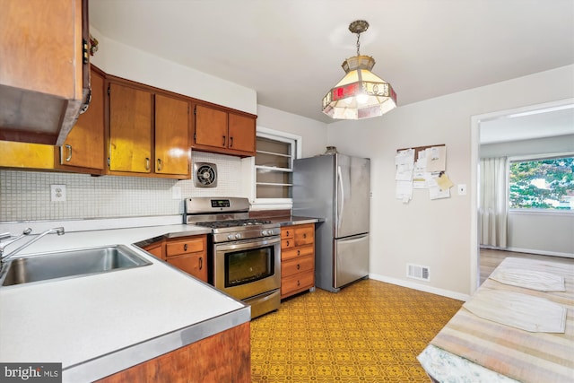 kitchen with appliances with stainless steel finishes, hanging light fixtures, sink, and decorative backsplash