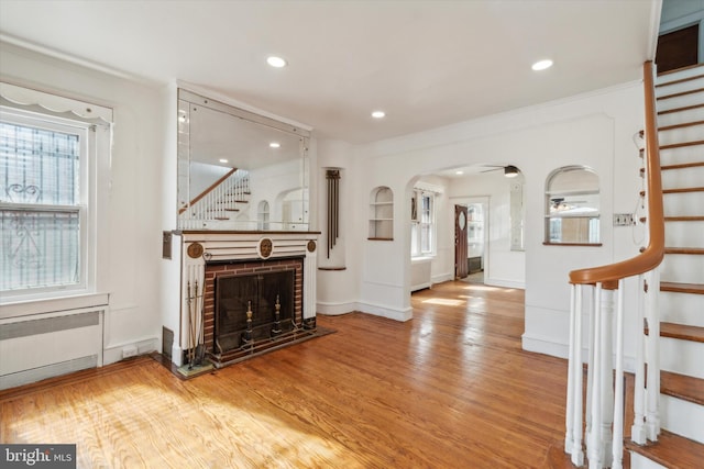 living room with a brick fireplace, radiator, and wood-type flooring