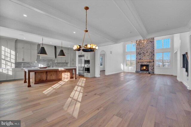kitchen with open floor plan, light wood-style floors, built in appliances, light countertops, and ornamental molding