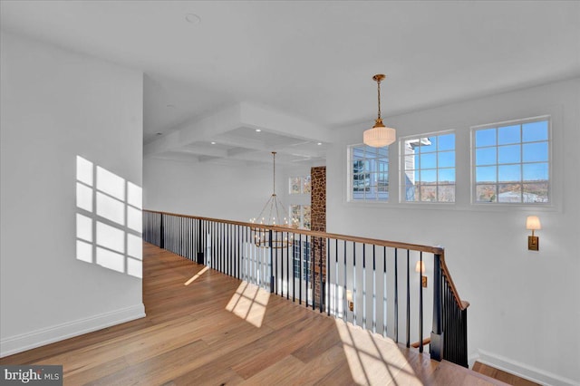 interior space featuring beamed ceiling, baseboards, wood finished floors, and an inviting chandelier