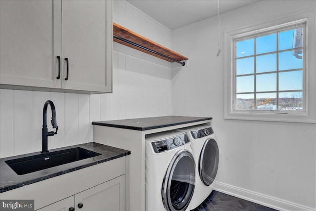 clothes washing area with washing machine and clothes dryer, baseboards, a sink, and cabinet space